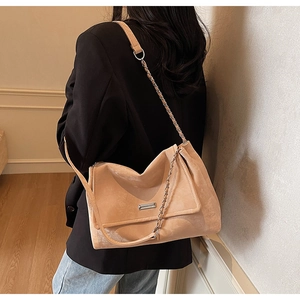 Vue latérale du sac fourre-tout en daim beige avec bandoulière chaîne et blazer