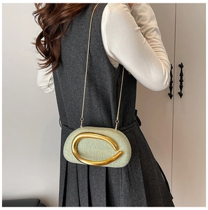 Detail of light green fabric evening bag featuring a large gold metal buckle and chain strap