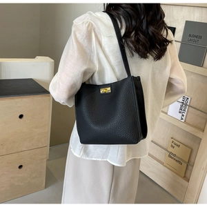 Détail du sac seau en cuir grainé noir avec fermoir rotatif en métal doré élégant
