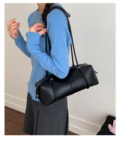 Detail of minimalist black leather bowling bag with long straps and vertical stitching