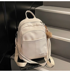 Detail of white lychee faux leather backpack with woven strap and brown plush charm