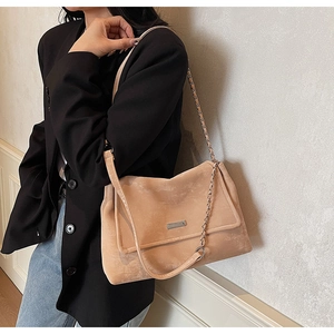 Détail du sac cabas en daim beige avec bandoulière en chaîne argentée et logo