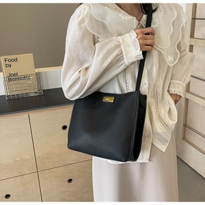 Detail of black lychee grain leather bucket bag with gold square twist lock on a model