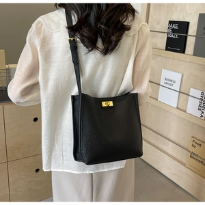 Détail du sac noir en cuir grainé avec fermoir rotatif doré et bandoulière réglable