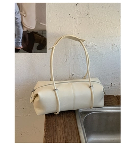 Macro detail of cream white cylinder tote bag with slim straps and silver metal rings