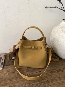 Mustard yellow bucket bag with teddy bear pendant on a rustic wooden table background