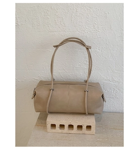 Close-up of beige leather bowling bag with vertical stitching and silver zipper hardware
