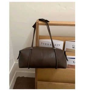 Macro view of minimalist dark brown leather bowling bag with silver rings and thin straps