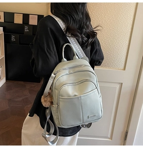 Detail view of mint green pebble leather backpack with decorative tassel and logo