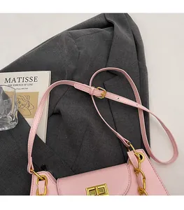 Detailed shot of pink leather baguette bag with gold chain and buckle on suit background