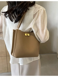Grand sac cabas en cuir beige avec fermoir doré porté par un mannequin dans un studio