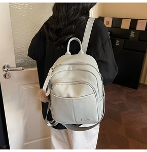 Detail view of stylish beige pebbled leather backpack with plush charm on a model