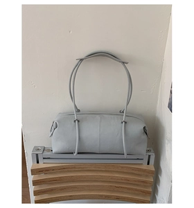 Detail shot of light grey textured leather shoulder bag with minimalist silver zipper