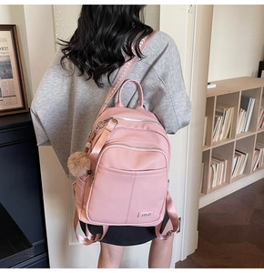 Detail of pink lychee grain PU leather backpack with jacquard strap and pompom charm