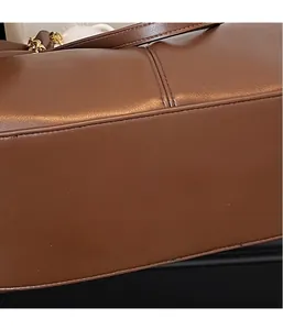 Detailed macro view of the smooth brown leather bottom and precise stitching of the tote bag