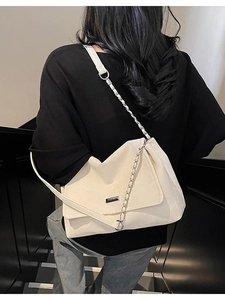 Sac fourre-tout crème chic avec chaîne en métal, porté par un mannequin sur fond noir