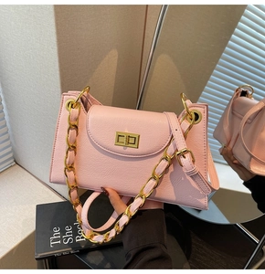 Détail du sac à main rose clair texturé avec chaîne dorée et fermoir rotatif métallique