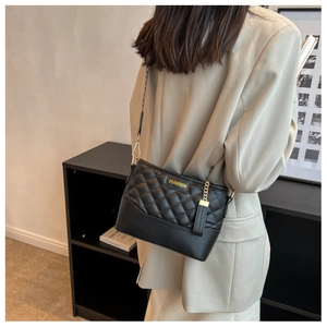 Detail einer schwarzen Stepptasche mit goldenen Beschlägen und Logo vor schickem Hintergrund
