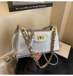 Détail d'un sac à main en cuir argenté avec fermoir doré et bandoulière en chaîne