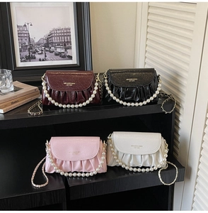 Close-up of pleated cloud bags with pearl handles and gold chain straps in four colors