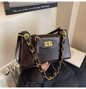 Détail de la texture cuir marron foncé et du fermoir doré de ce sac à bandoulière chic