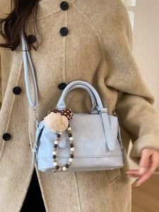 Light blue faux leather Boston bag with plush charm on a tweed coat model outfit