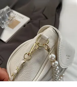 Detail of warm white pleated leather handbag featuring gold hardware and pearl chain strap