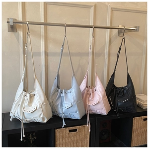 Detail view of four studded bucket bags in white, light blue, pink, and black colors