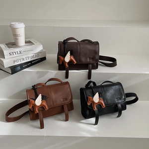 Detailed close-up of retro crossbody bags in dark brown, camel, and black with pony charms