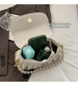 Spacious interior of beige pleated cloud bag with pearl chain and gold magnetic clasp