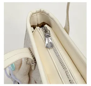 Détail de la fermeture éclair argentée sur sac seau blanc avec breloque lapin