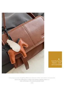 Detail of brown leather flap bag with contrast stitching and a Pegasus horse charm