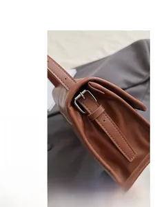 Detailed close-up of brown leather bag featuring adjustable silver metal buckle strap