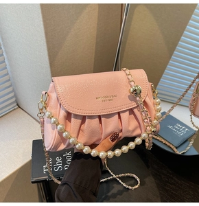Detail of pink pleated crossbody bag featuring elegant pearl and gold chain strap