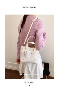 Détail du sac seau floral avec pendentif lapin porté par un mannequin en studio