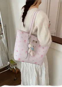 Pink tote bag detail with cartoon prints and a cute plush bear pendant accessory