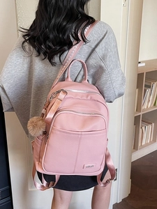Pink litchi texture PU leather backpack with plush pompom on a model in a cozy room