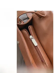 Detail shot of a brown leather handbag showing silver zipper hardware and interior lining