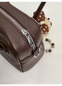 Detailed close-up of custom silver metal zipper and dark brown litchi grain leather