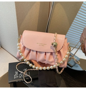 Detail of pink pleated bag featuring gold chain and large pearl shoulder strap accents