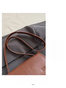 Detailed view of the brown leather shoulder strap and neat stitching on a vintage bag