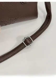 Detail of lychee pattern leather handbag with silver buckle and adjustable shoulder strap