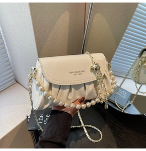Detail of cream pleated leather bag featuring pearl handle and gold hardware buckles