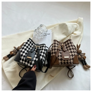 Close-up of retro plaid bucket bags with leather trim and cute rabbit charm accessories