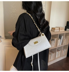 Detail of white pleated leather shoulder bag with gold chain and metal twist lock closure