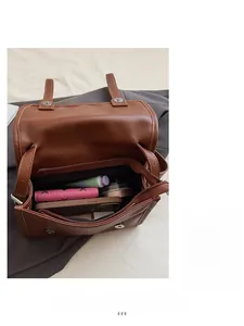 Detail view of the brown leather bag interior showing a large main compartment and zip pocket