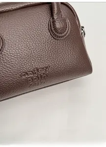 Close-up of pebble grain dark brown leather texture with embossed onjey coin 2dm logo