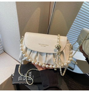 Detailed shot of white beaded chain bag with golden logo and pearl strap accent