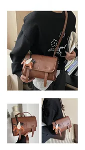 Detailed view of a brown vintage leather crossbody bag with horse charm and buckle straps