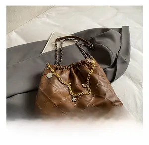 Detail showing brown quilted tote bag with star charms and pearl chain decoration